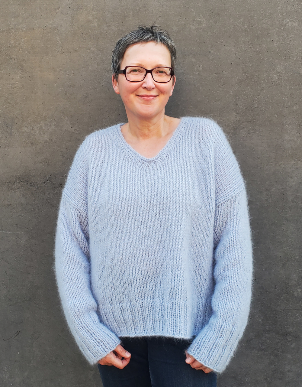 Modell träght hellblauen Mohairpullover mit V-Ausschnitt
